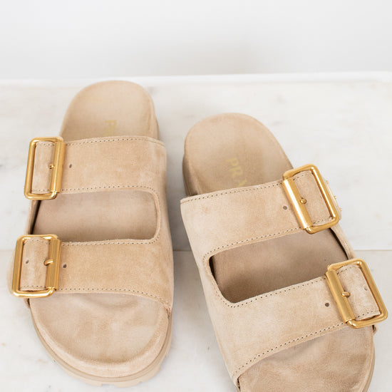 Beige sandals with gold buckles on a white background