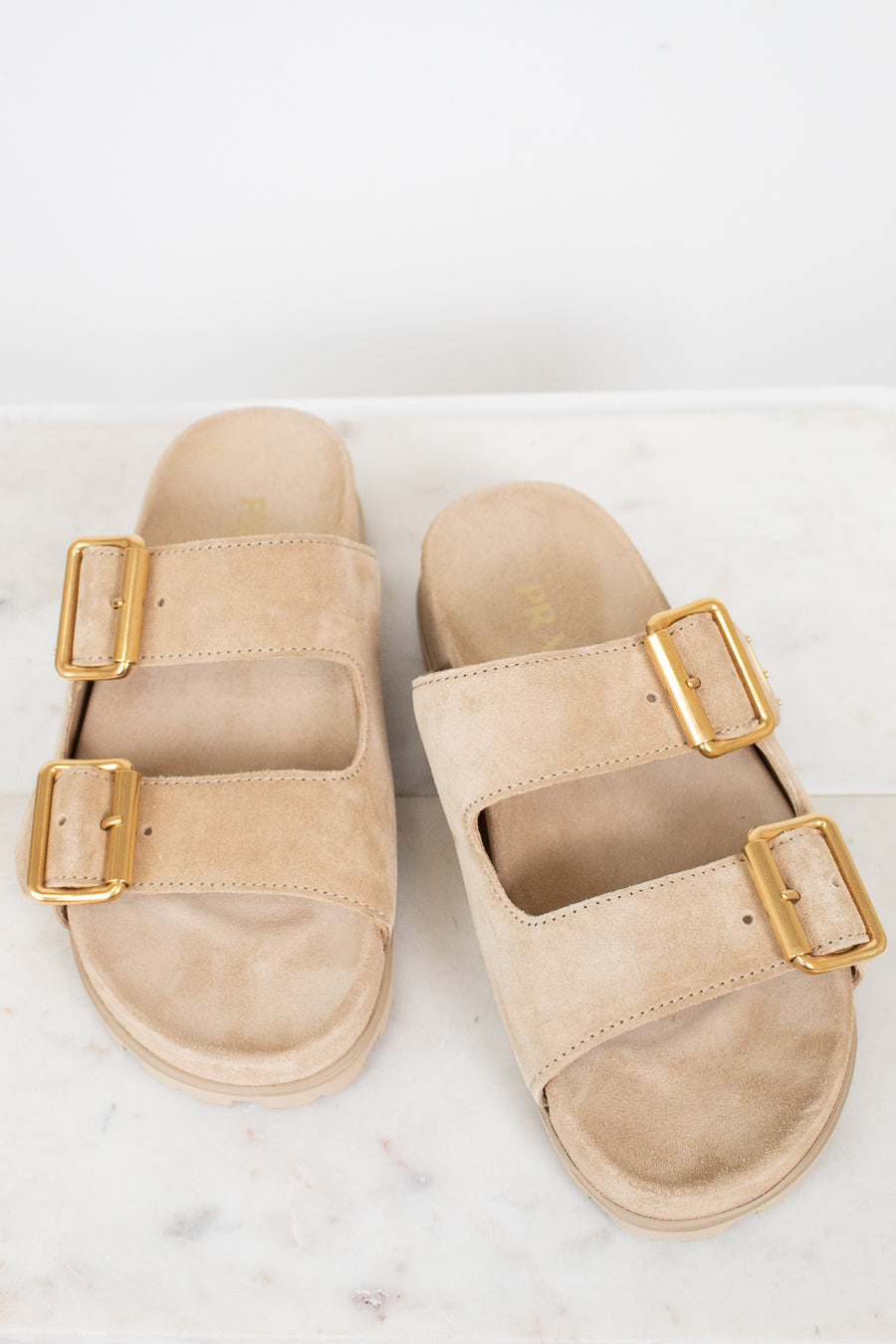 Beige sandals with gold buckles on a white background