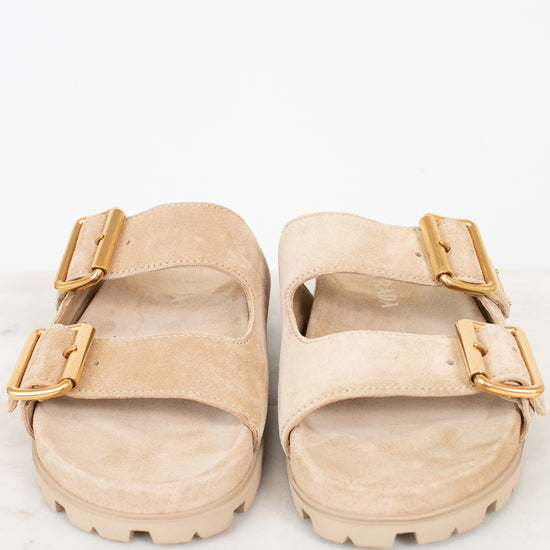 Beige sandals with gold buckles on a white background