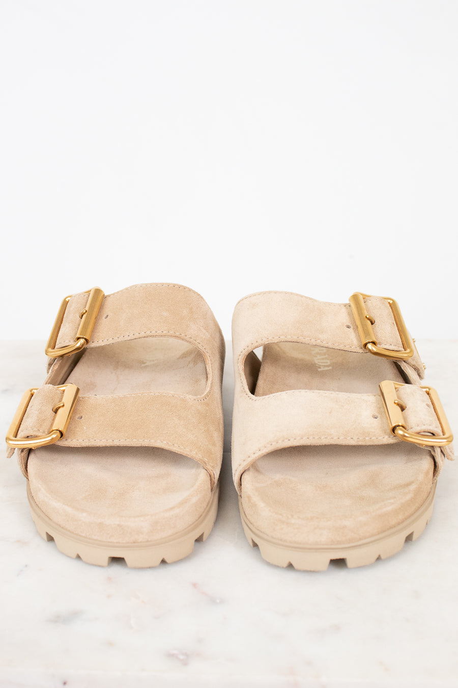 Beige sandals with gold buckles on a white background