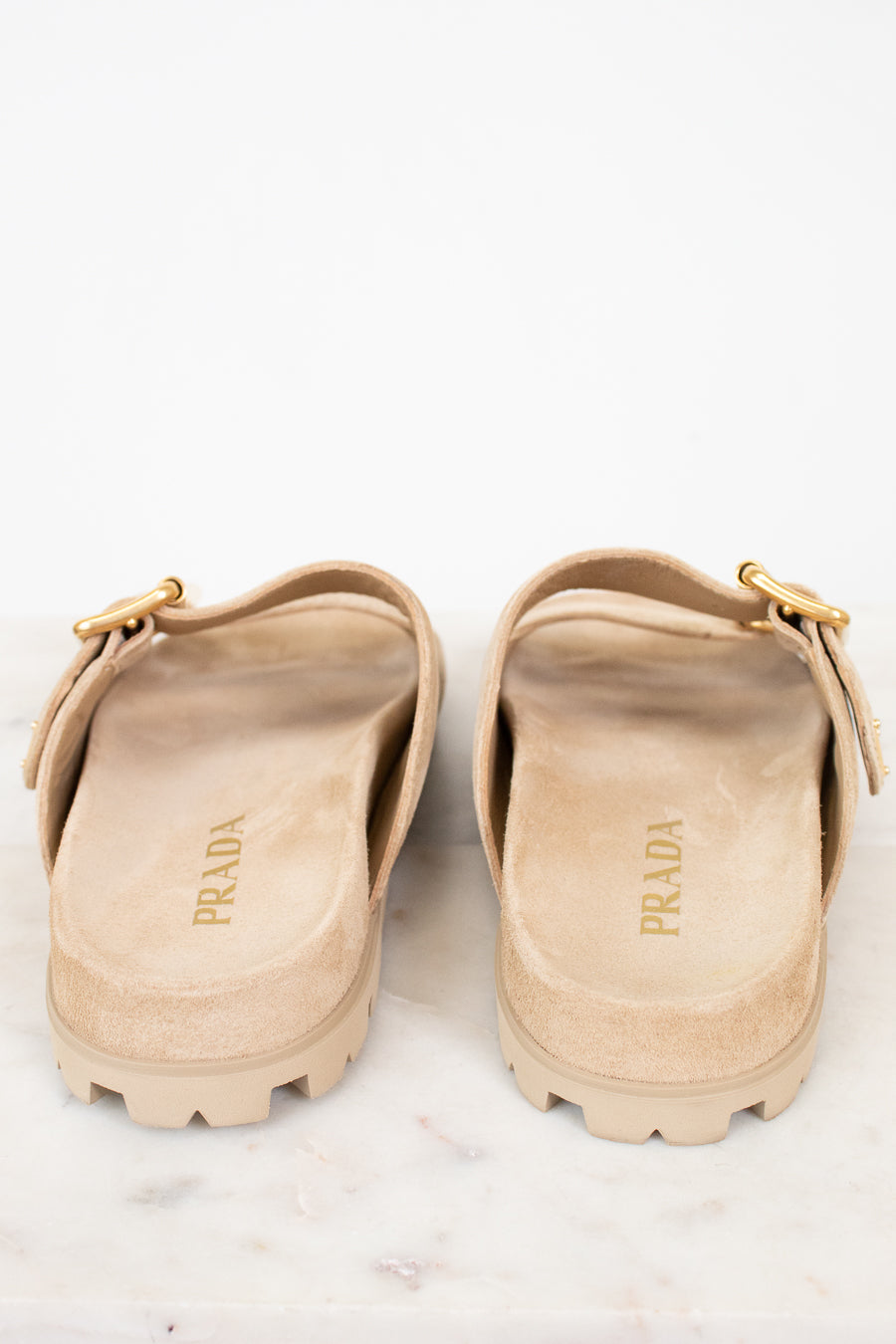Pair of beige Prada sandals on a white background