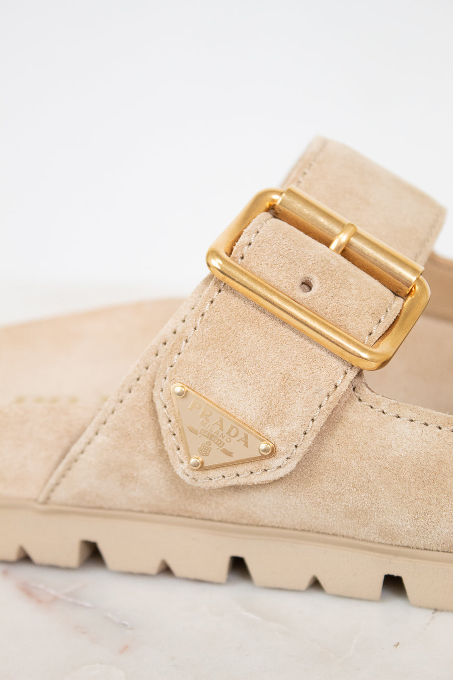 Beige suede sandals with gold buckle on a light background