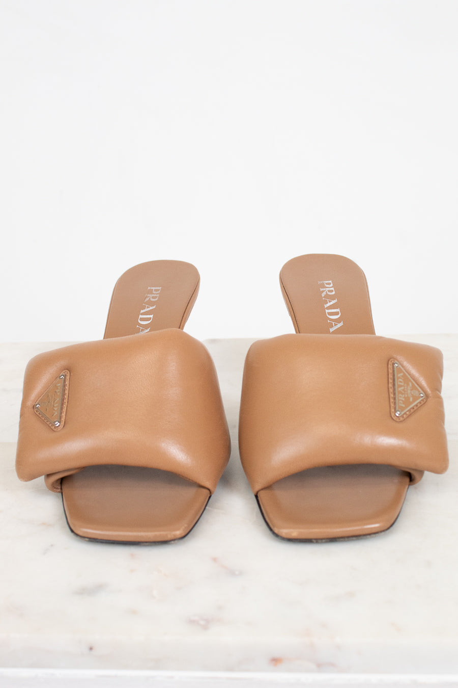 Pair of tan Prada sandals on a white background
