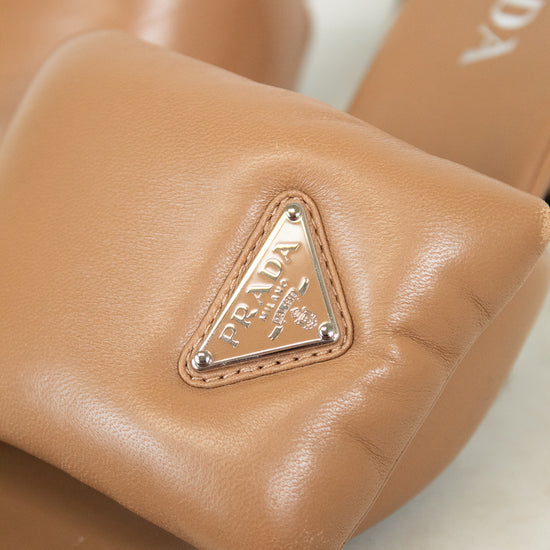 Close-up of tan leather sandals with Prada logo on a light background