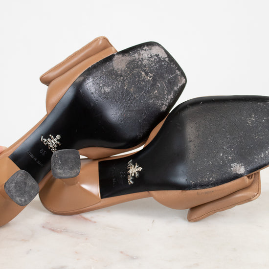 Pair of brown shoes with black soles on a light marble surface