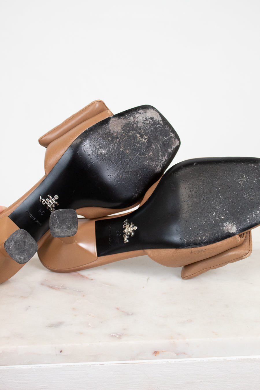 Pair of brown shoes with black soles on a light marble surface