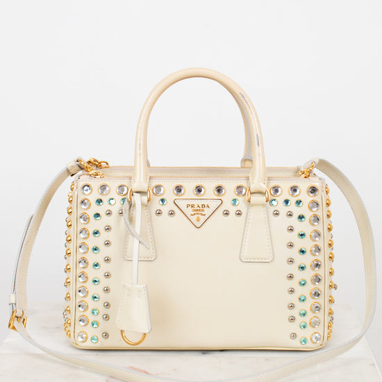 Cream-colored handbag with gemstone embellishments on a white background