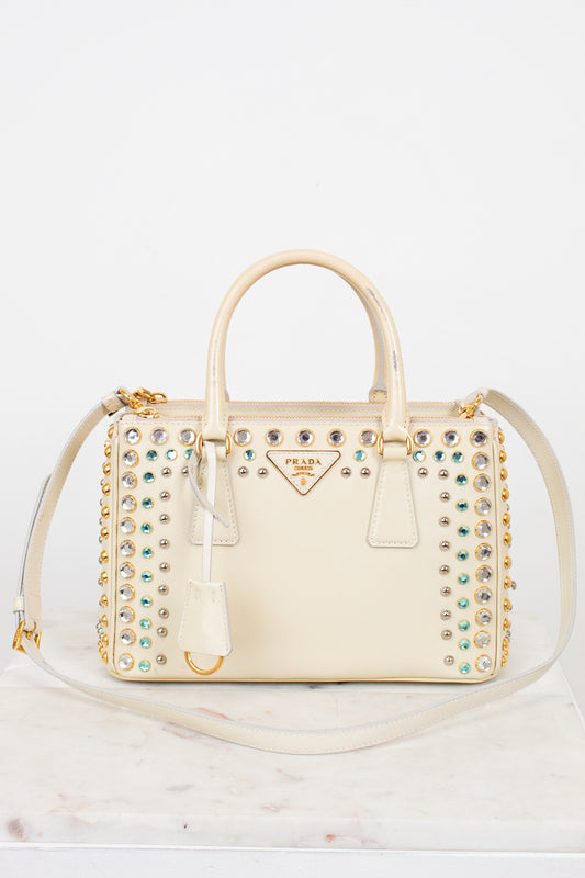 Cream-colored handbag with gemstone embellishments on a white background