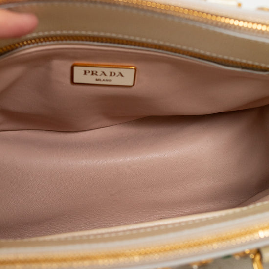 Close-up of a Prada handbag with a gold zipper and beige interior.