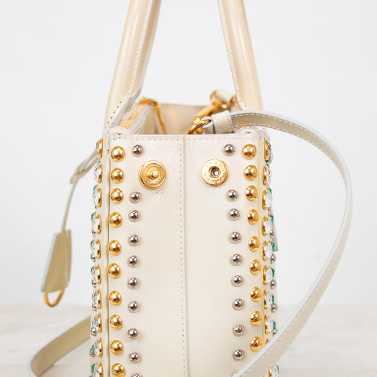 Cream handbag with gold and silver studs on a light background