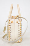 Cream handbag with gold and silver studs on a light background