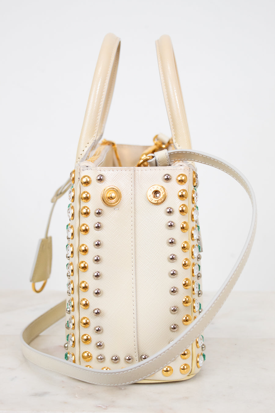 Cream handbag with gold and silver studs on a light background