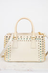 Cream-colored handbag with gold and multi-color gemstone embellishments on a light gray background