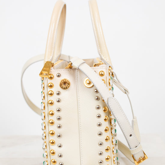 Cream handbag with gold studs and handles on a white background