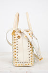 Cream handbag with gold studs and handles on a white background