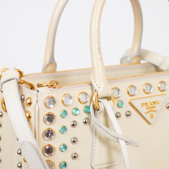 Beige handbag with decorative studs and gemstones on a white background