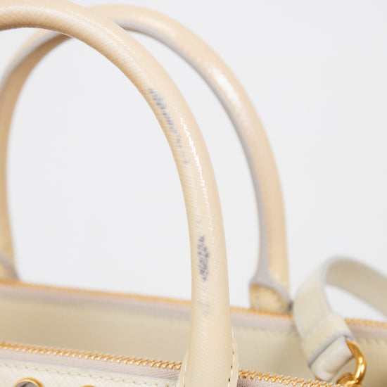 Close-up of strap on beige handbag with decorative stones on a light gray background showing stain on handle 