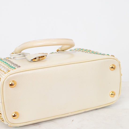Bottom exterior  of cream-colored handbag with gold accents on a white background