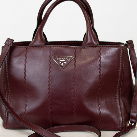 Maroon leather handbag with Prada logo on a light background