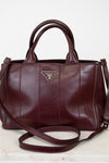 Maroon leather handbag with Prada logo on a light background