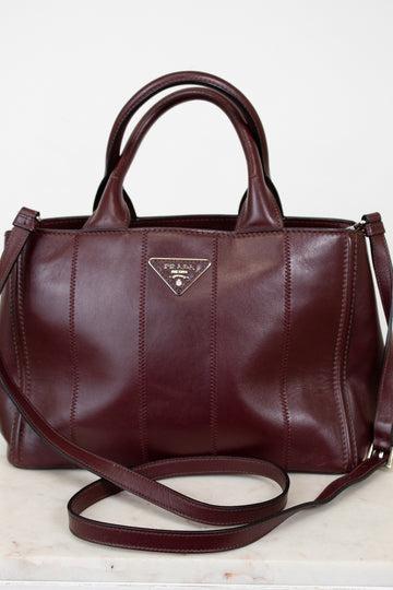 Maroon leather handbag with Prada logo on a light background