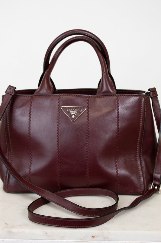 Maroon leather handbag with Prada logo on a light background