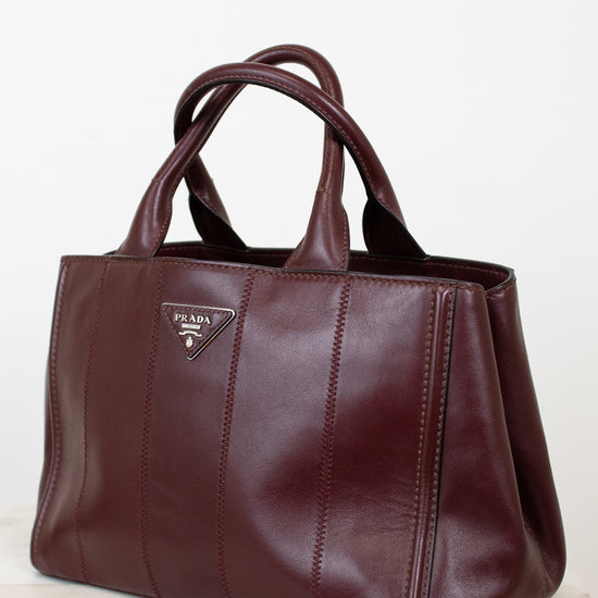Maroon leather handbag with Prada logo on a light background