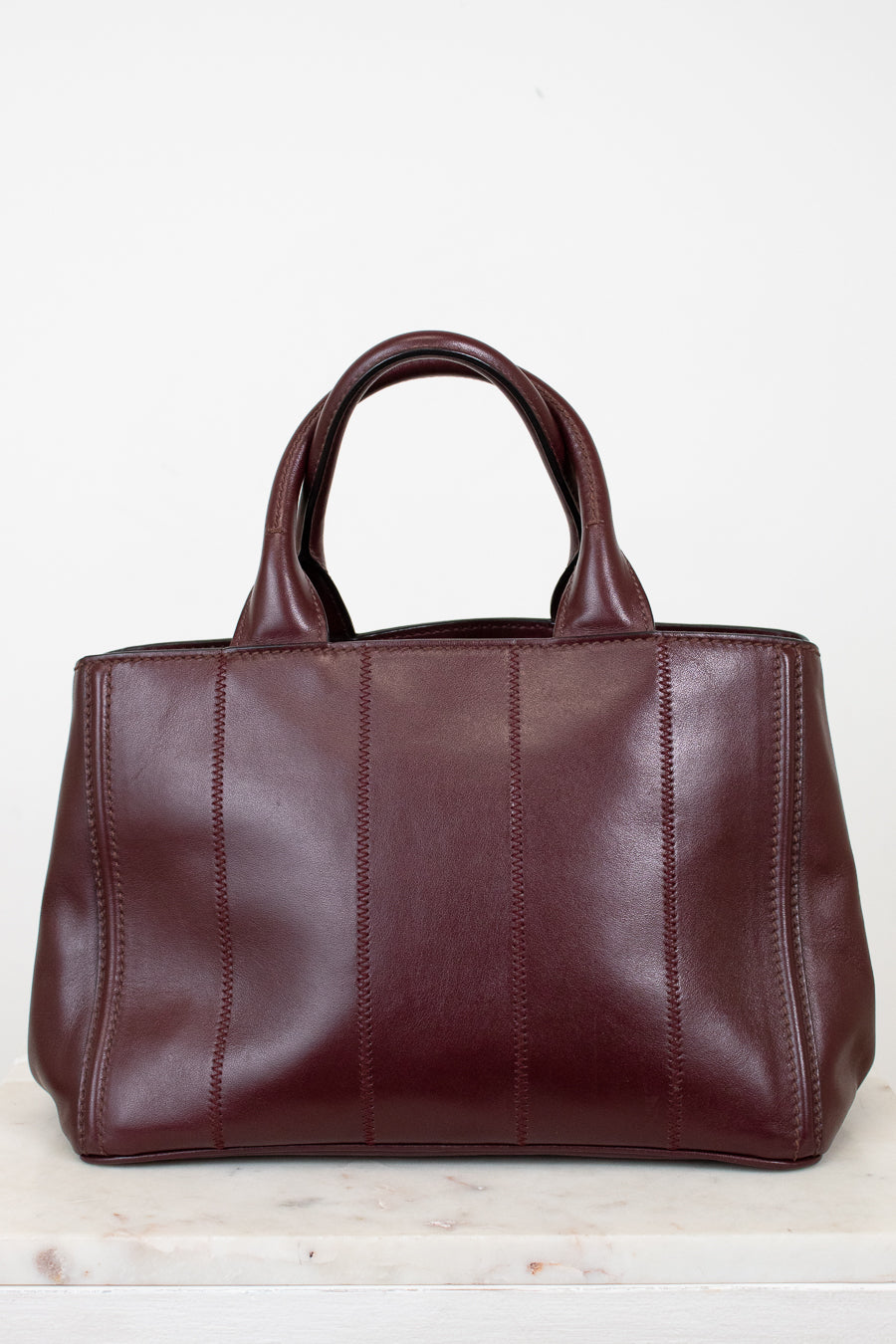 Maroon leather handbag on a light background