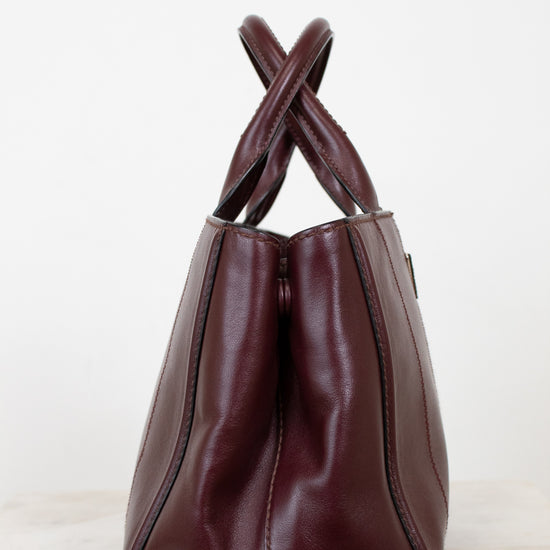 Maroon leather handbag with leather handle on a white background