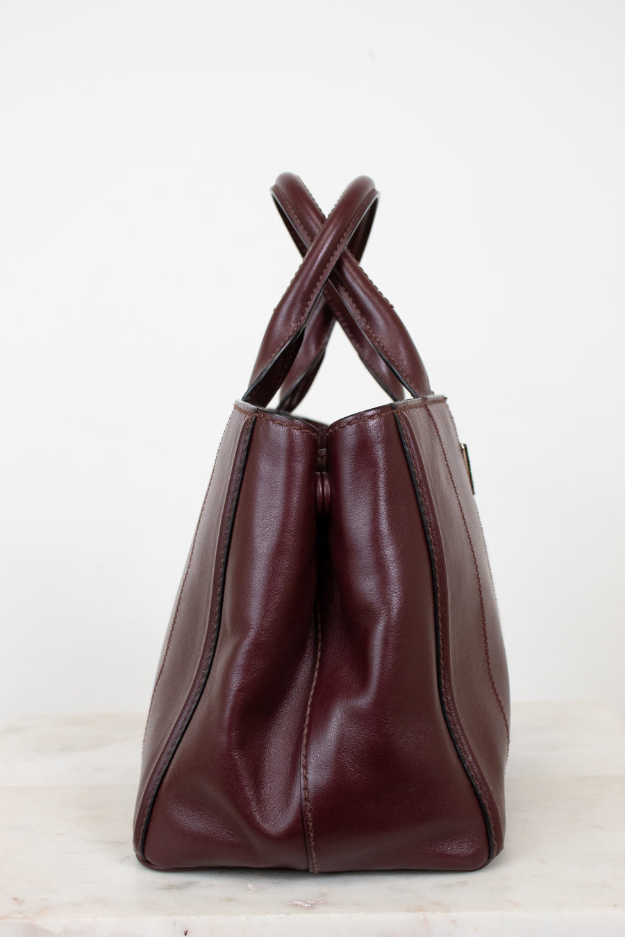 Maroon leather handbag with leather handle on a white background