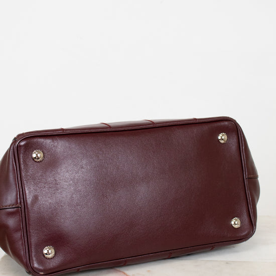 Brown leather handbag with gold feet on a light background