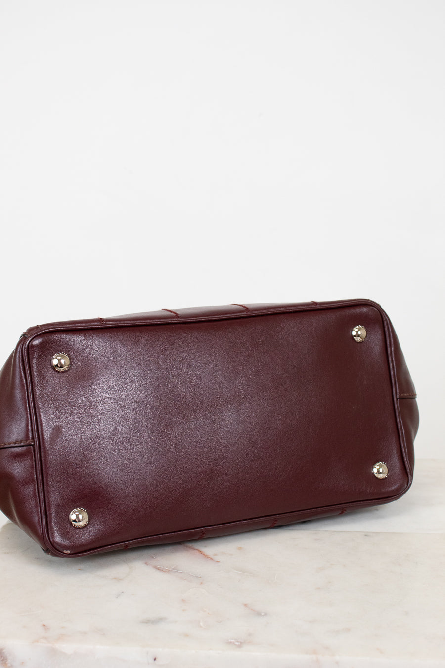 Brown leather handbag with gold feet on a light background