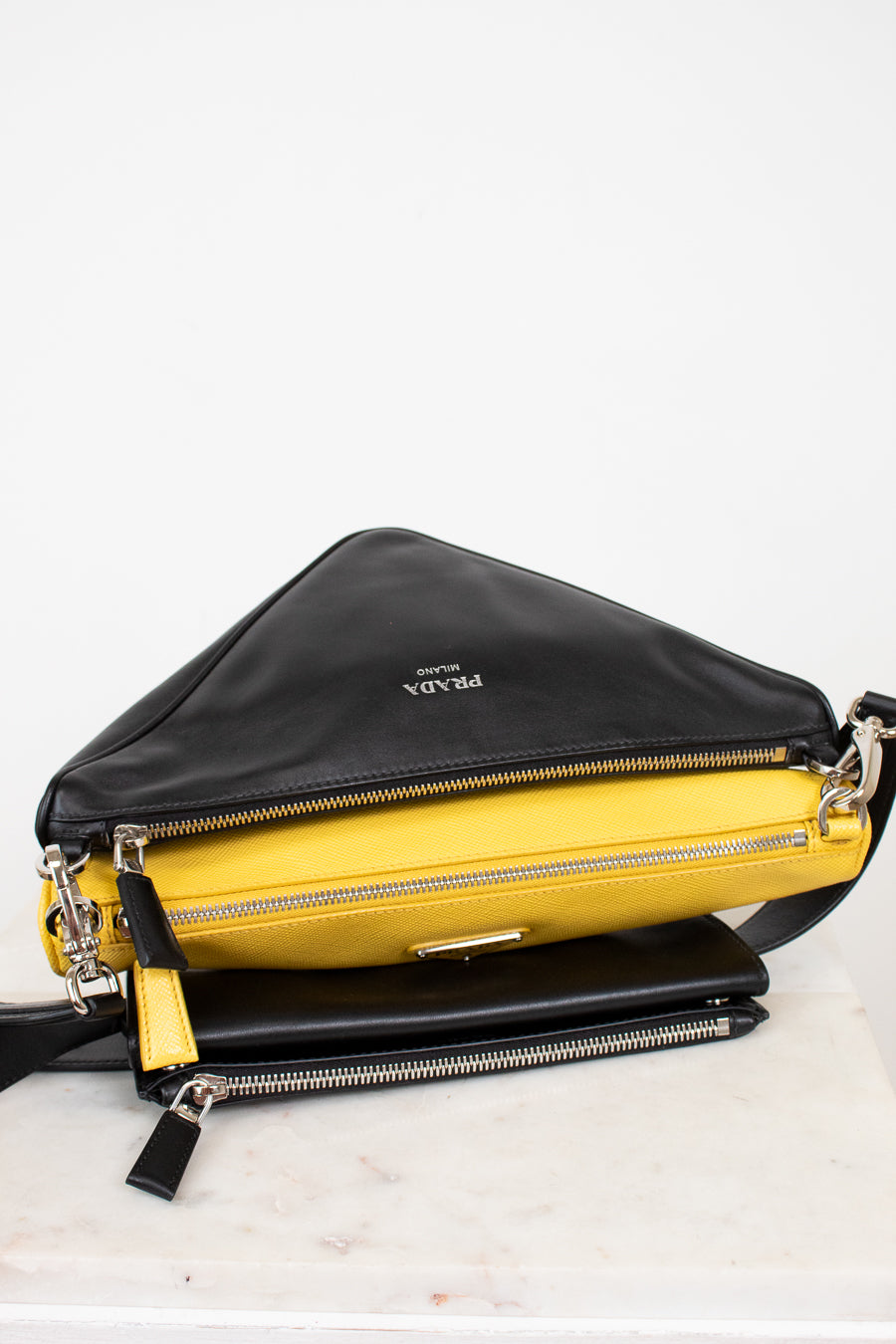 Black and yellow handbag with Prada logo on a white background