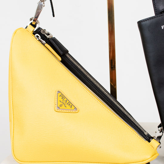 Yellow Prada bag with a black strap on a light background