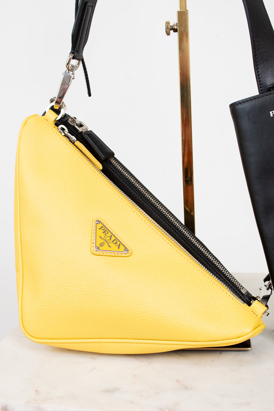 Yellow Prada bag with a black strap on a light background