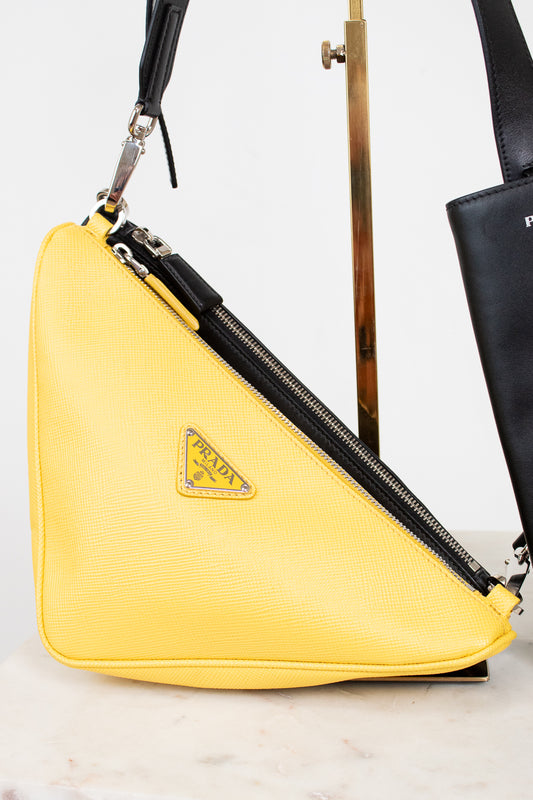 Yellow Prada bag with a black strap on a light background