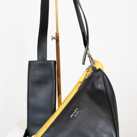 Black leather handbag with yellow pouch on a white background