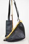 Black leather handbag with yellow pouch on a white background