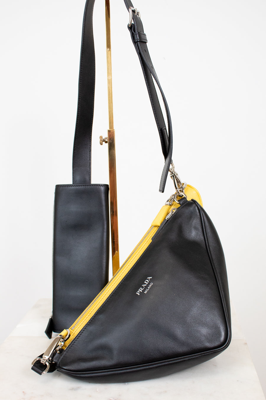 Black leather handbag with yellow pouch on a white background