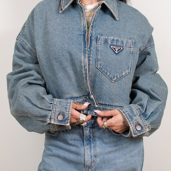 Person wearing a blue denim jacket with a brand logo on a plain background