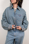 Person wearing a blue denim jacket with a brand logo on a plain background
