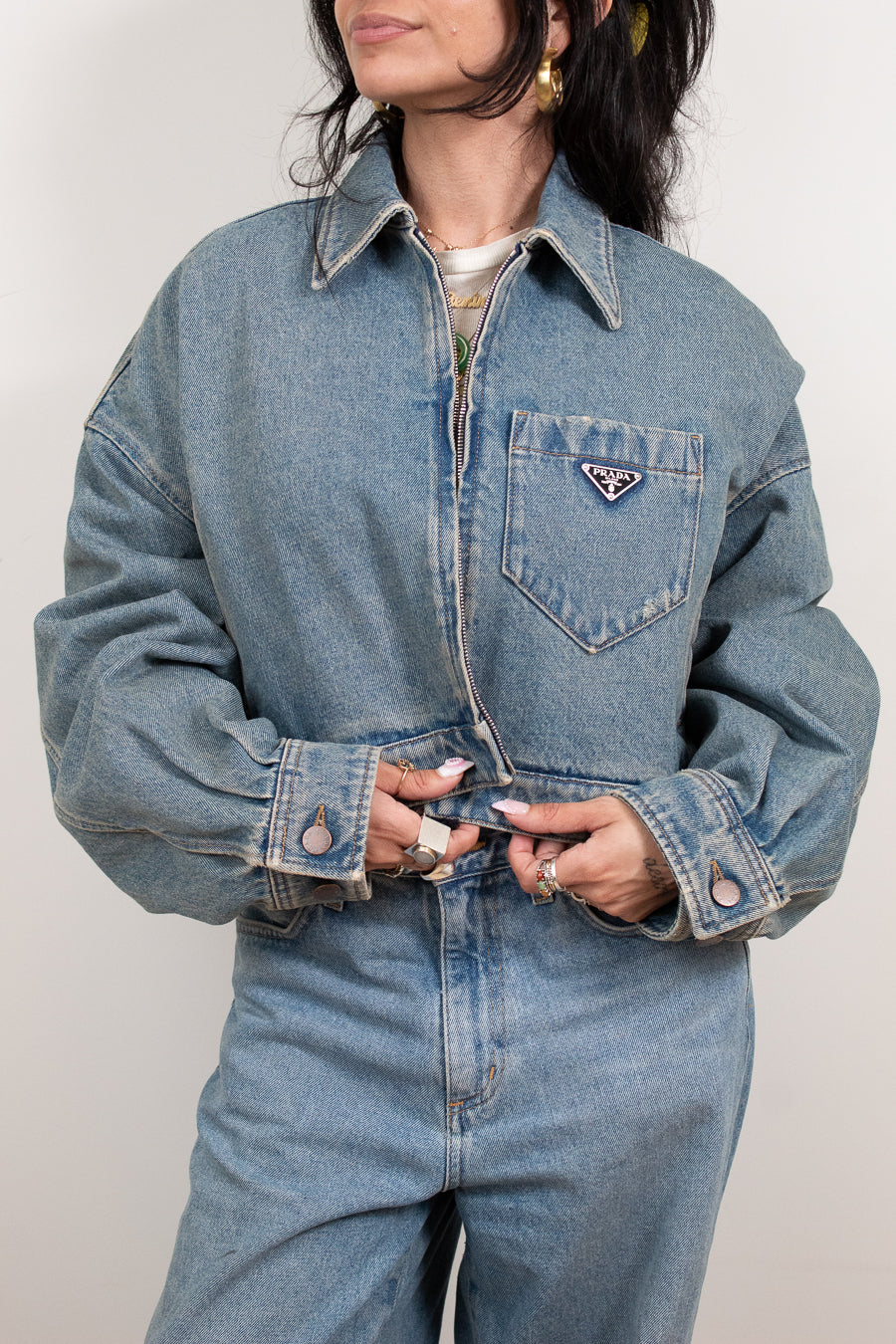 Person wearing a blue denim jacket with a brand logo on a plain background
