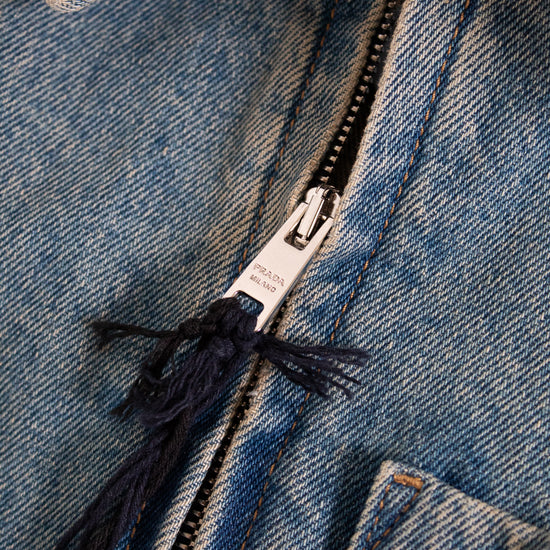 Close-up of a blue denim jacket zipper with brand label