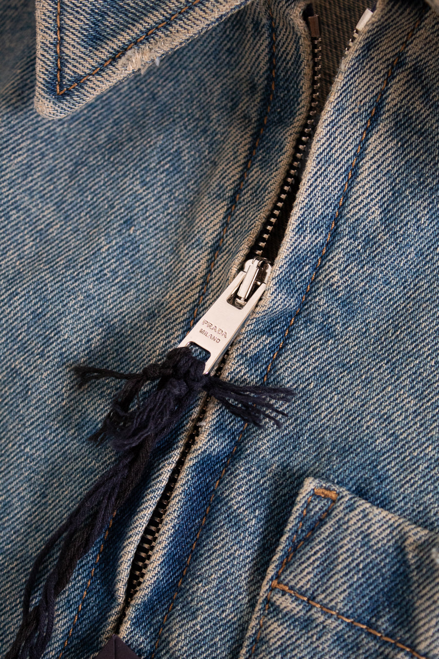 Close-up of a blue denim jacket zipper with brand label