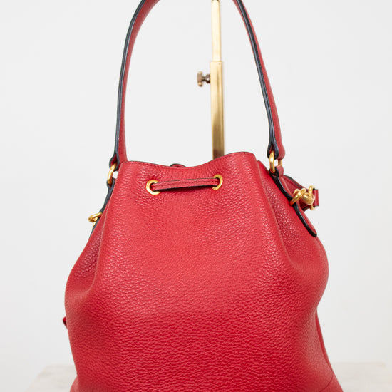 Red leather handbag with gold accents on a light gray background