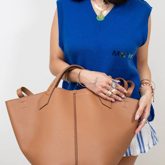 Woman holding a brown tote bag against a plain background