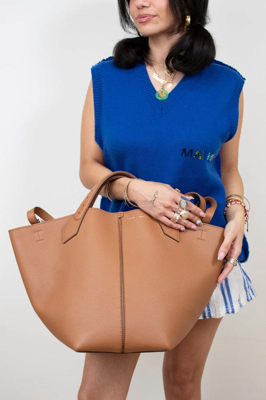 Woman holding a brown tote bag against a plain background