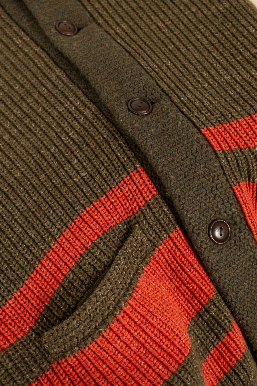 Close-up of a green and orange striped cardigan with buttons.