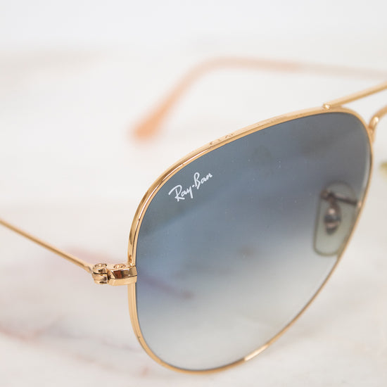 Gold-framed sunglasses with gradient lenses on a marble surface