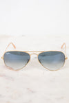 Gold-framed sunglasses with blue gradient lenses on a white marble surface